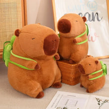 Load image into Gallery viewer, Adorable capybara plush toys with tiny green backpacks, available in multiple sizes! Perfect for cuddles, décor, or gifting to capybara lovers.
