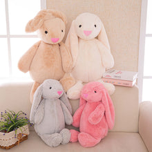 Load image into Gallery viewer, Four plush bunny toys in different colors sitting on a couch.