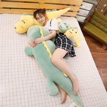 Load image into Gallery viewer, girl hugging green dinosaur plushie while lying on yellow dinosaur plushie